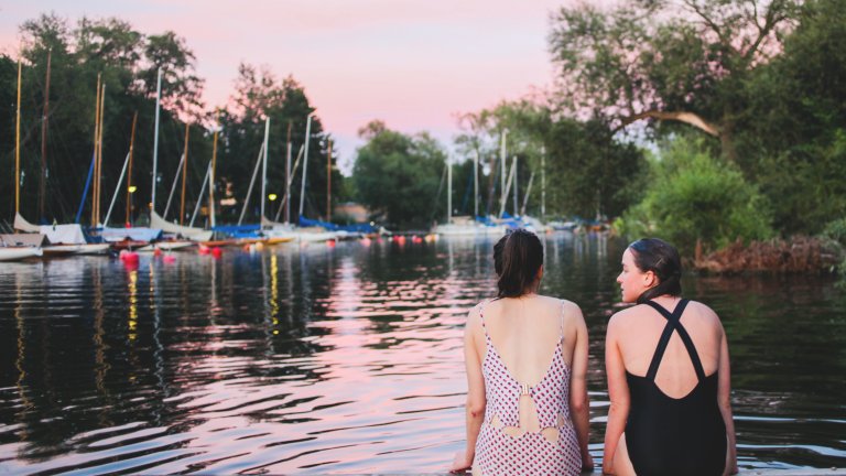 Two girls sitting on pier. Summer in the city.